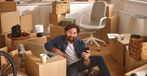 Iemand zit op de grond, omringd door kartonnen dozen in een pas verhuisd huis.