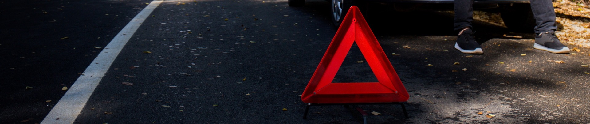 Een man heeft pech met de auto en zit met zijn handen in het haar in de kofferbak